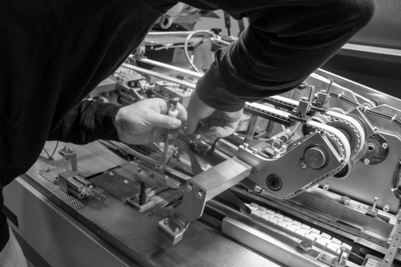 A technician setting up an inserting machine on the production floor